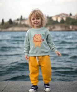 Aslan sweatshirt’lü ve sarı pantolonlu çocuk.