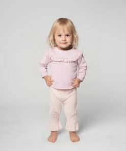 Pembe üst ve pantolonlu ayakta duran yürümeye başlayan çocuk.