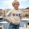 Sweatshirt ve kot pantolonlu gülümseyen çocuk.