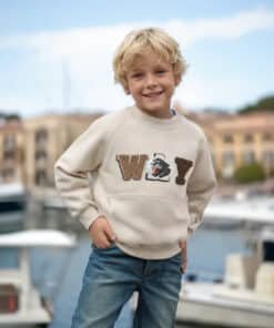 Sweatshirt ve kot pantolonlu gülümseyen çocuk.