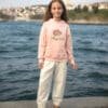 Pembe kapşonlu ve beyaz pantolonlu kız.