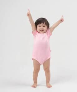 Pembe tulumlu gülümseyen bebek.