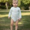 Bodysuit giymiş ayakta duran yürümeye başlayan çocuk.