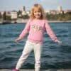 Pembe sweatshirt ve beyaz pantolonlu kız.