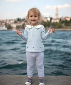 Açık mavi denizci temalı kıyafet giyen gülümseyen yürümeye başlayan çocuk.