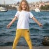 Beyaz tişört ve sarı pantolon giyen gülümseyen kız.
