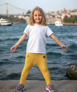 Beyaz tişört ve sarı pantolon giyen gülümseyen kız.